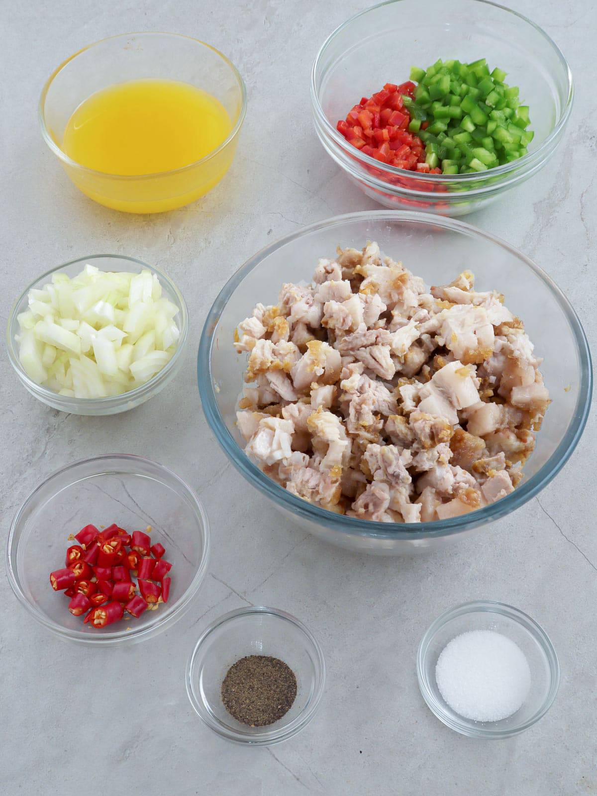 chopped lechon kawali, bell peppers, onions, chili peppers, lemon juice, salt, and pepper in individual bowls