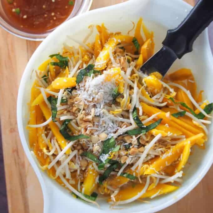 mixing Thai mango salad in a white bowl