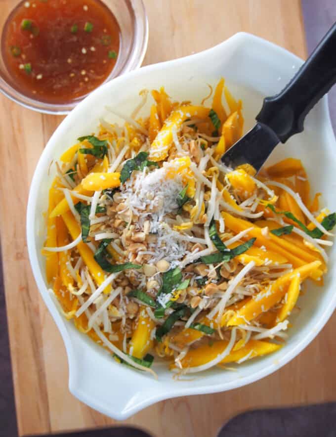 mixing Thai mango salad in a white bowl