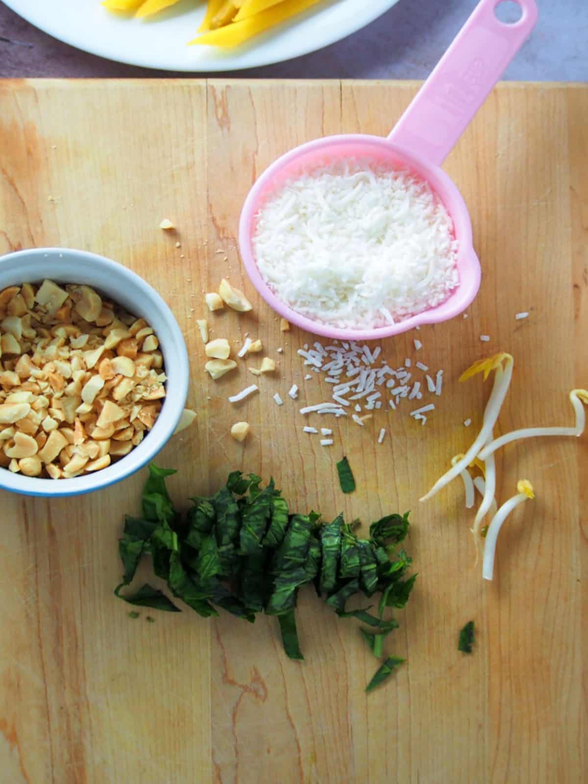 chopped peanuts, shredded coconut, shredded basil on a cutting board