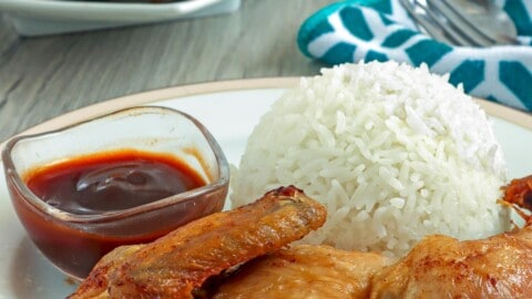 cut-up fried chicken with steamed rice on a white plate