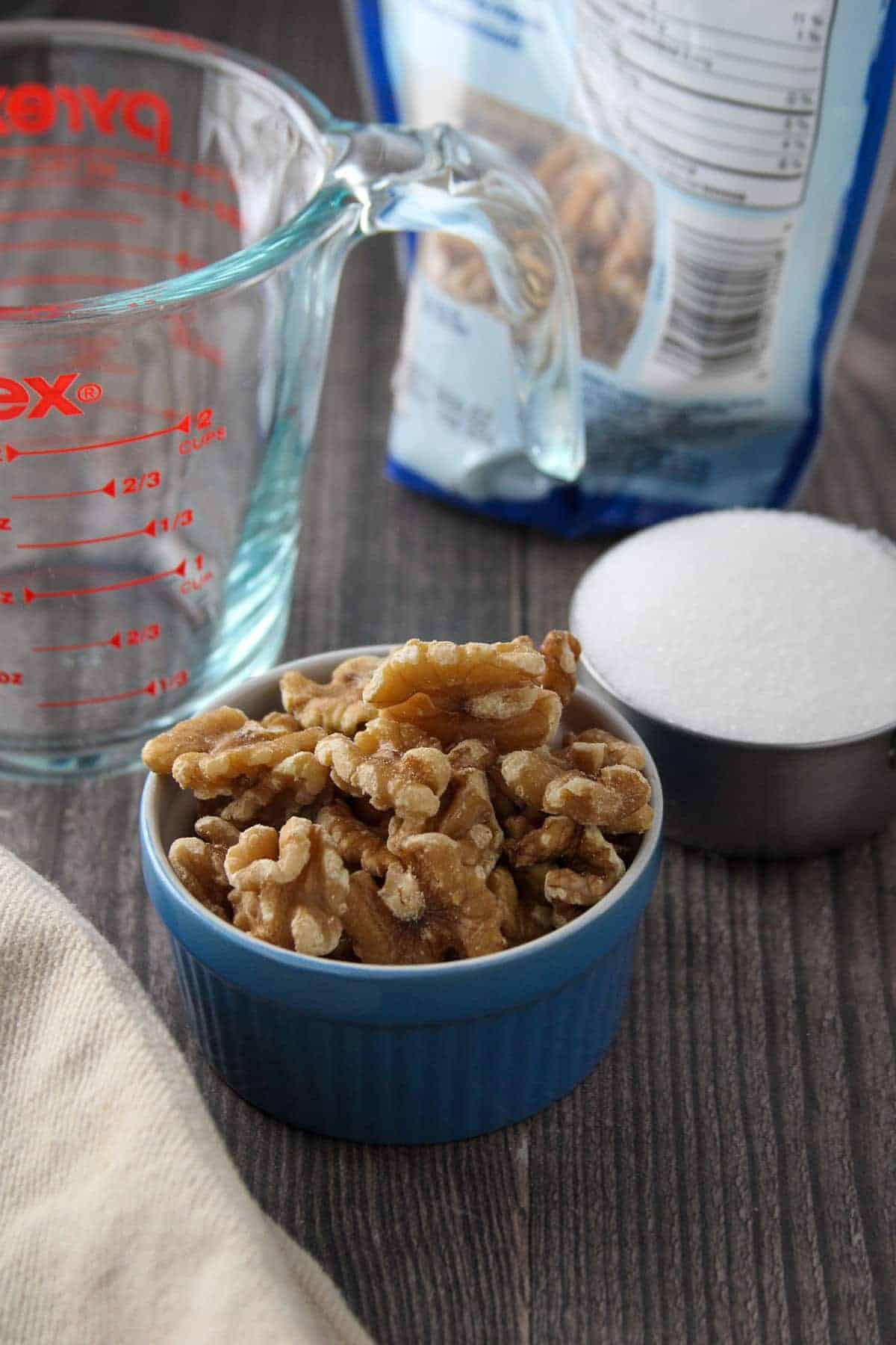 walnuts in a blue bowl, measurig cup, and sugar