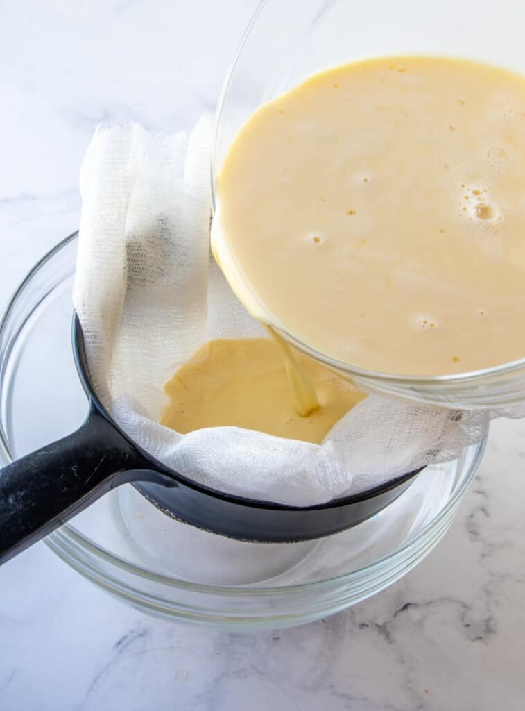 straining custard mixture in a cheesecloth-lined fine-mesh sieve