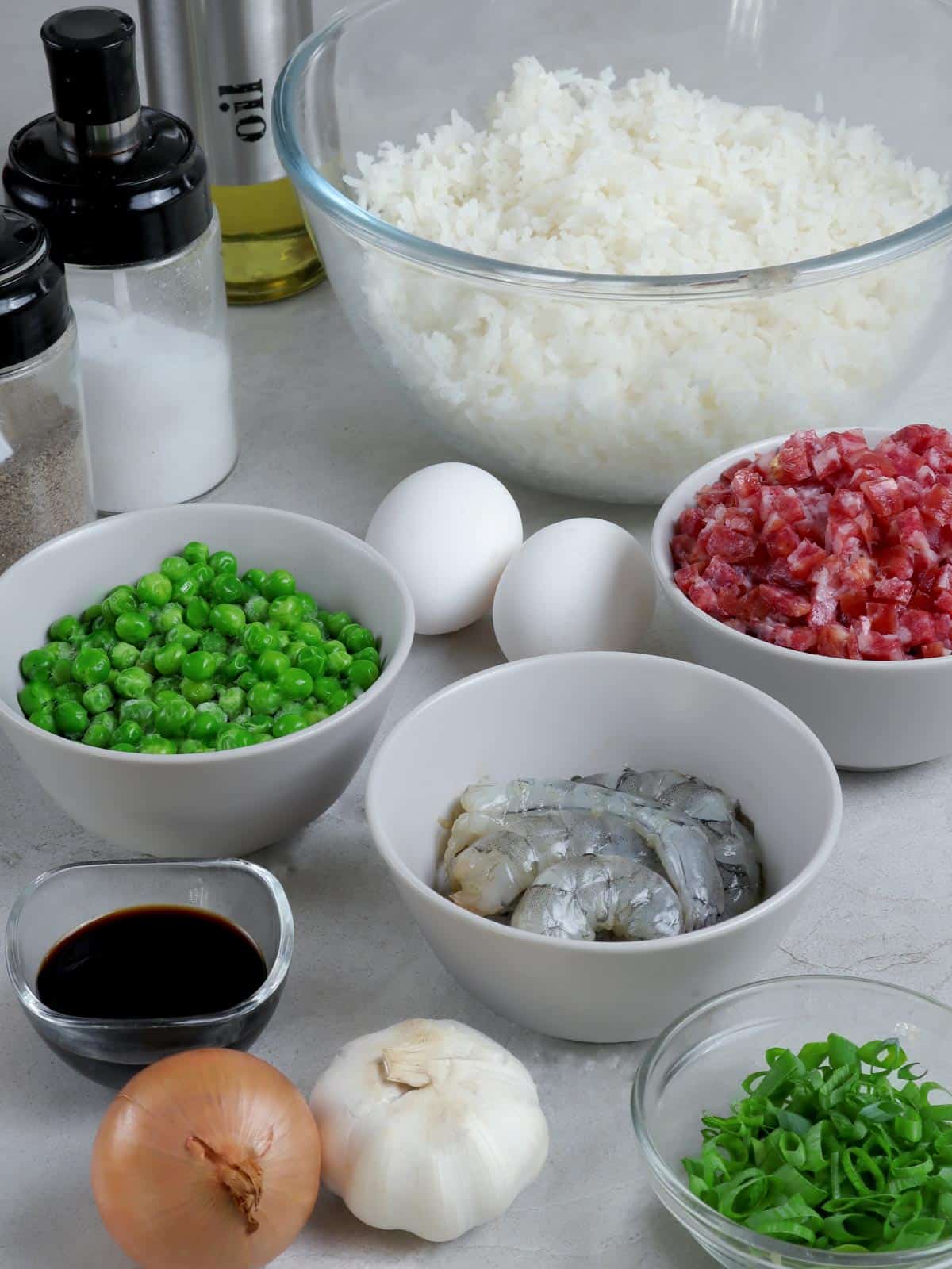 cold cooked rice in a bowl, green peas, Chinese sausage, garlic, onions, and green onions for fried rice