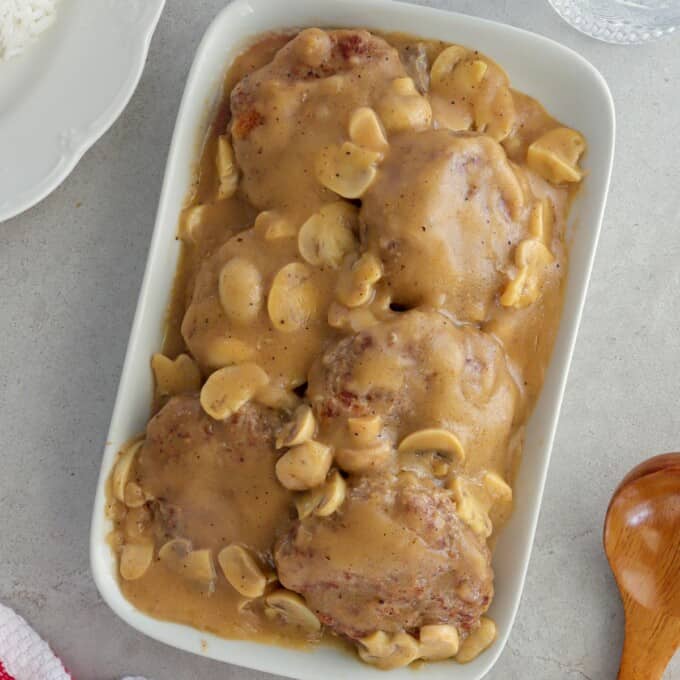 burger patties with mushroom gravy on a white serving platter.