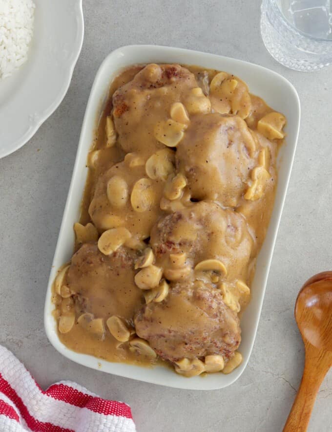 burger patties with mushroom gravy on a white serving platter.