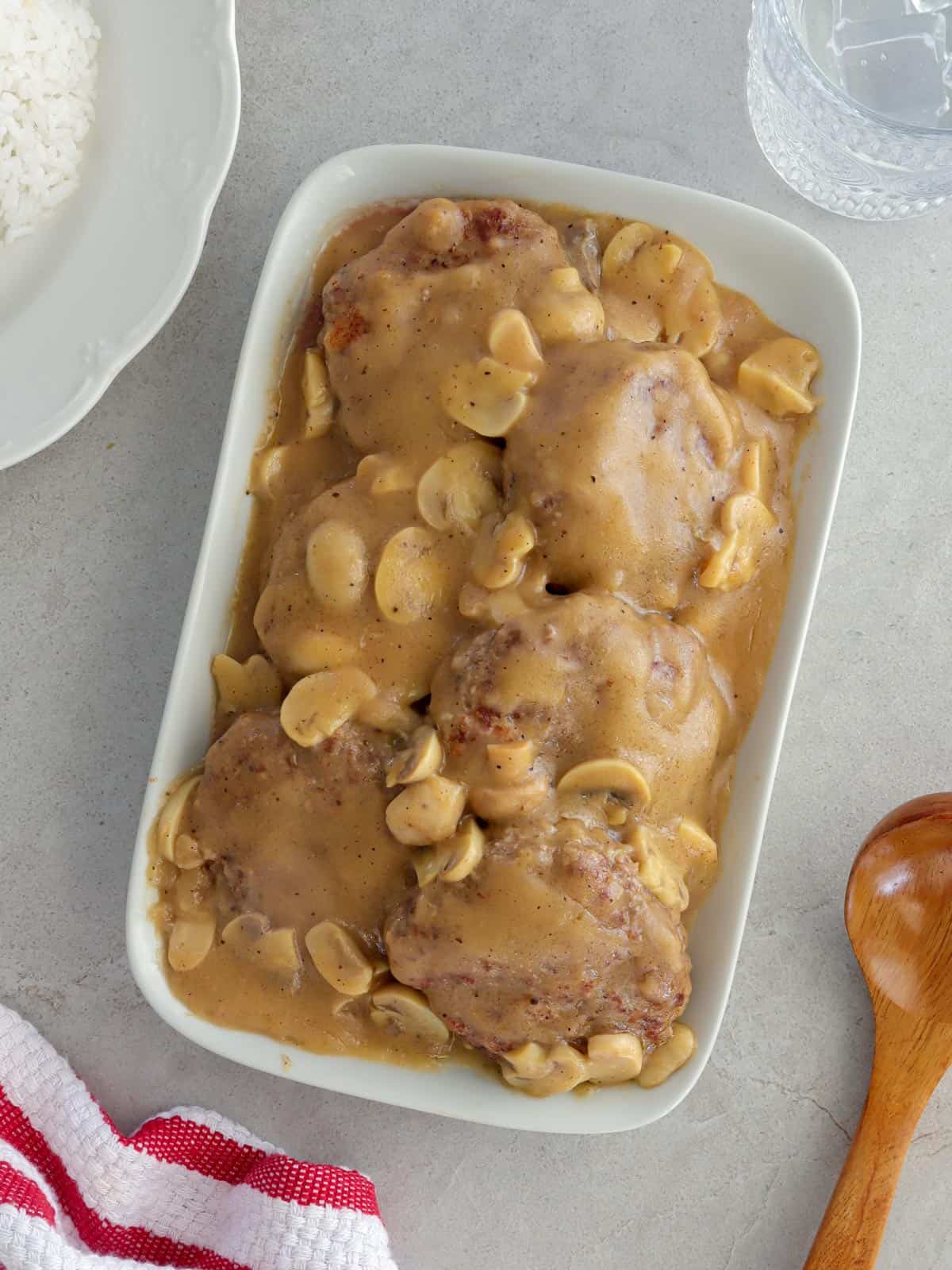 burger patties with mushroom gravy on a white serving platter.