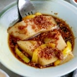 eating kalamay with latik, syrup, and langka with a fork in a bowl