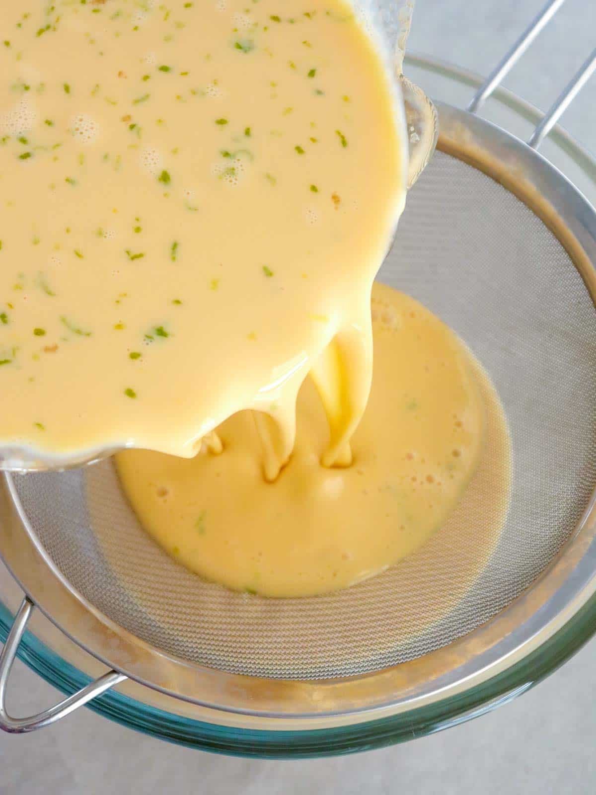 straining the custard mixture in a fine mesh sieve