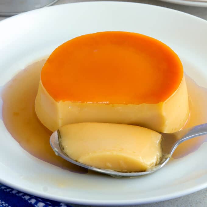 whole eggs leche flan on a white plate with a spoon