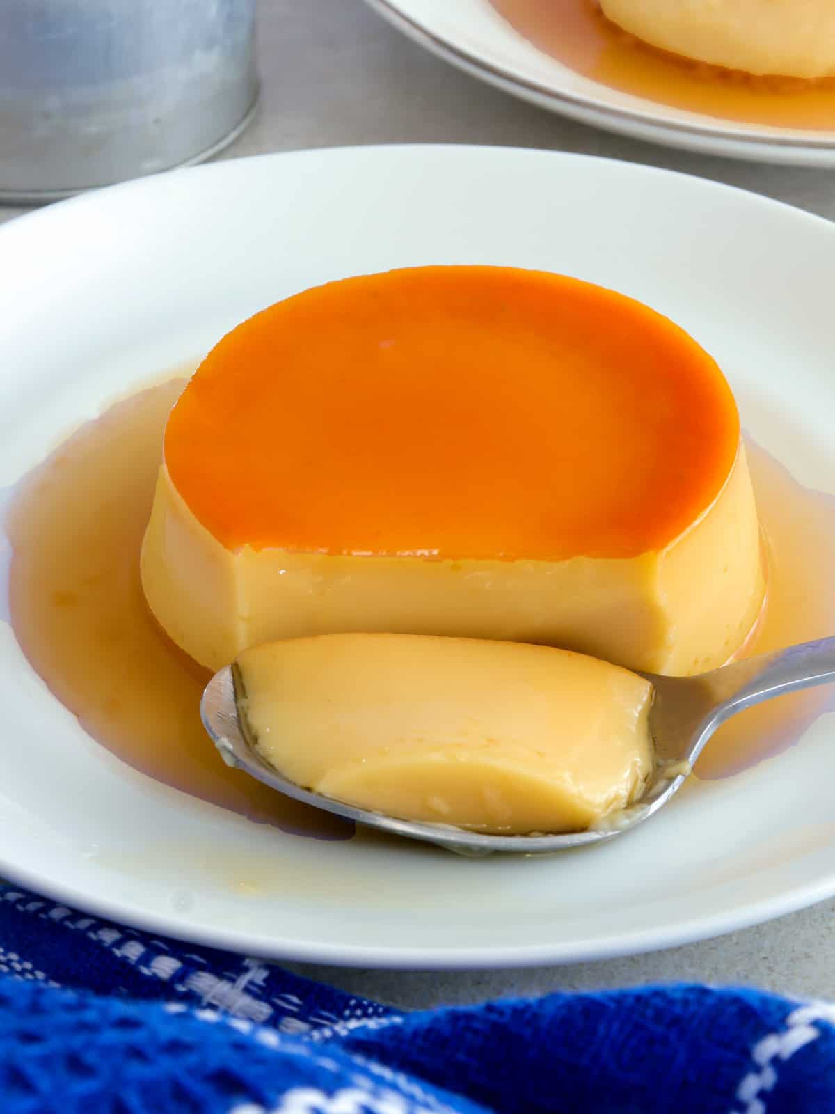 whole eggs leche flan on a white plate with a spoon
