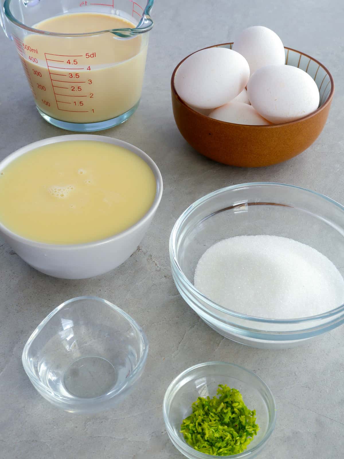 eggs, condensed milk, evaporated milk, sugar, water, lime zest in bowls