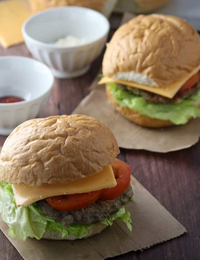 Banana Heart Burgers with lettuce, tomato, and cheese on a wooden board