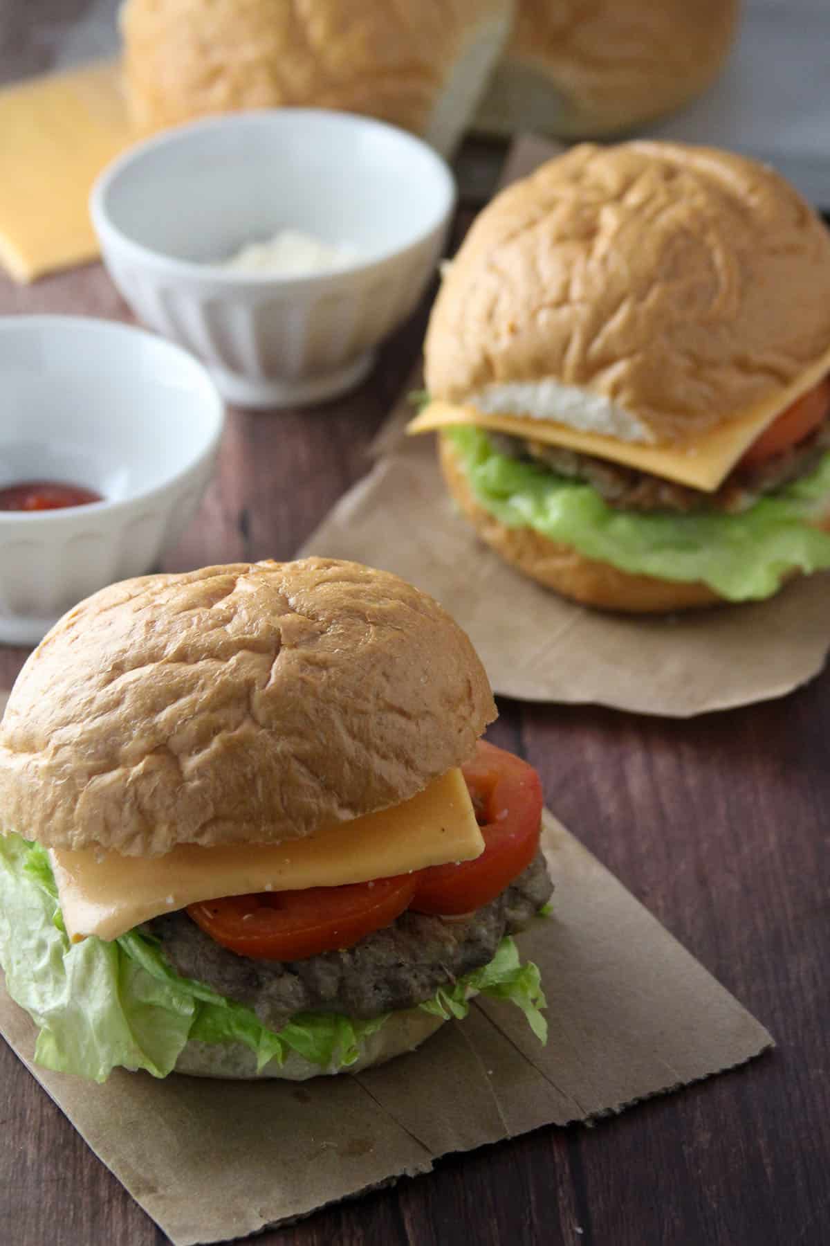 Banana Heart Burgers with lettuce, tomato, and cheese on a wooden board