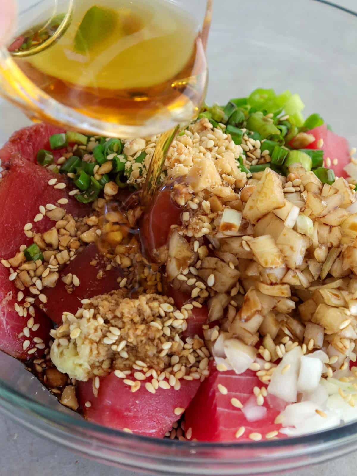 pouring sesame oil to a bowl of poke