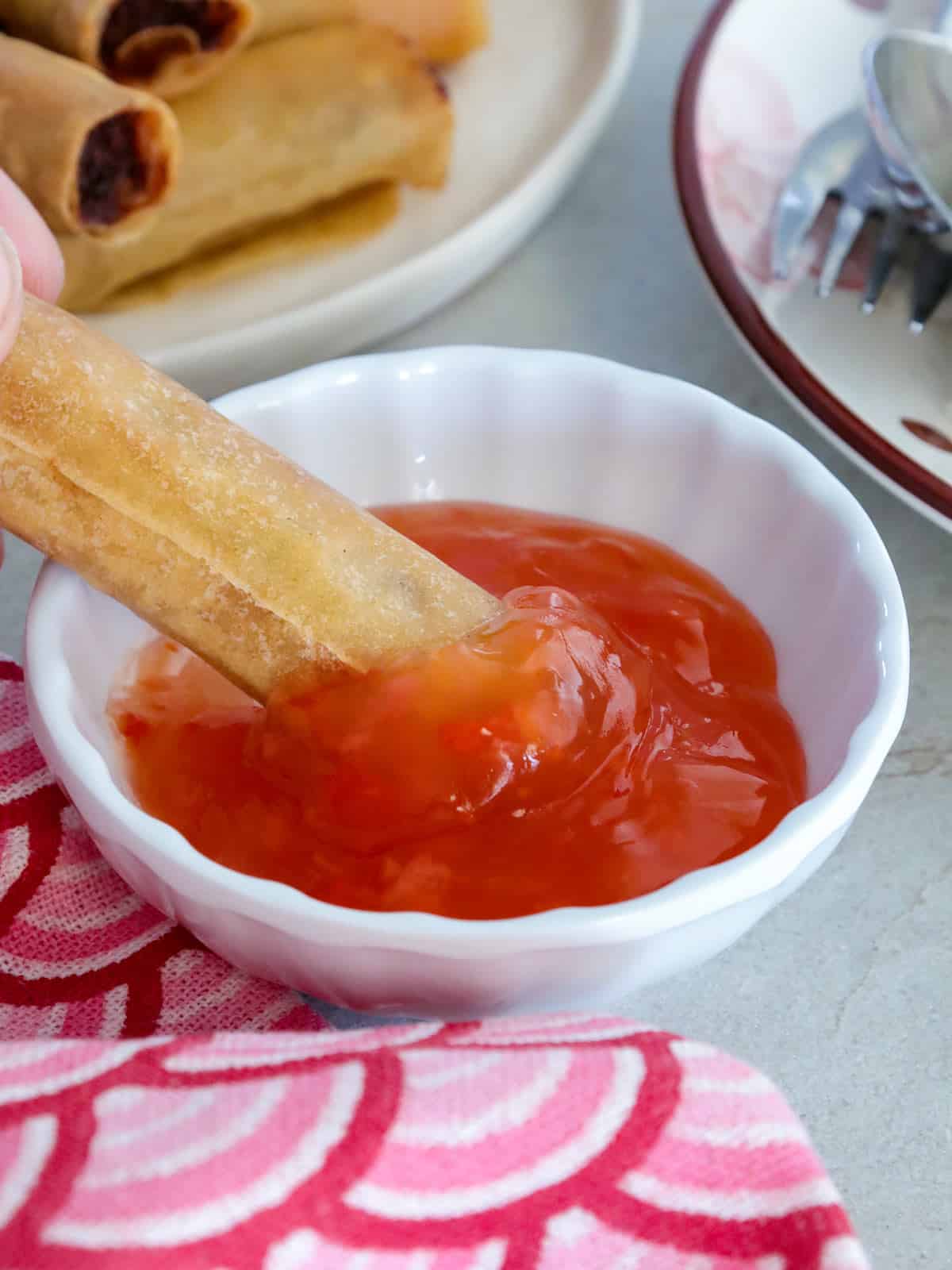 dipping fried lumpia shanghai in sweet chili sauce