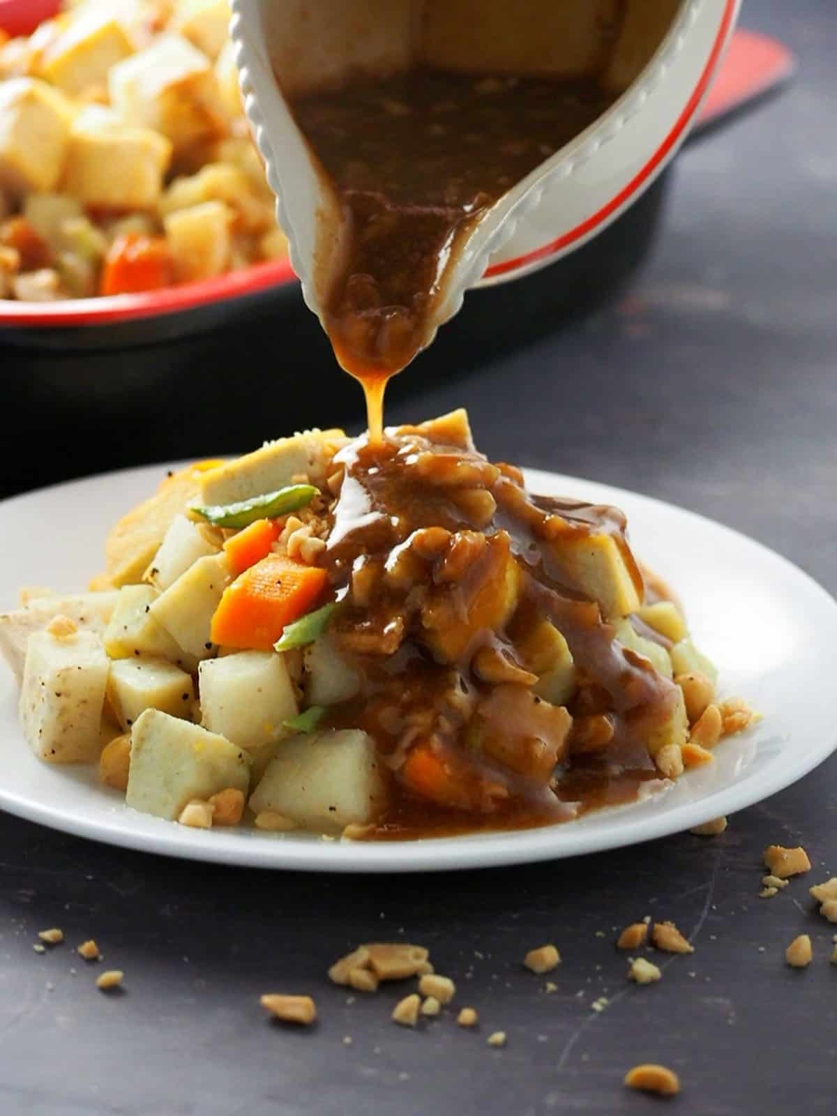 pouring peanut sauce over lumpiang hubad on a white plate