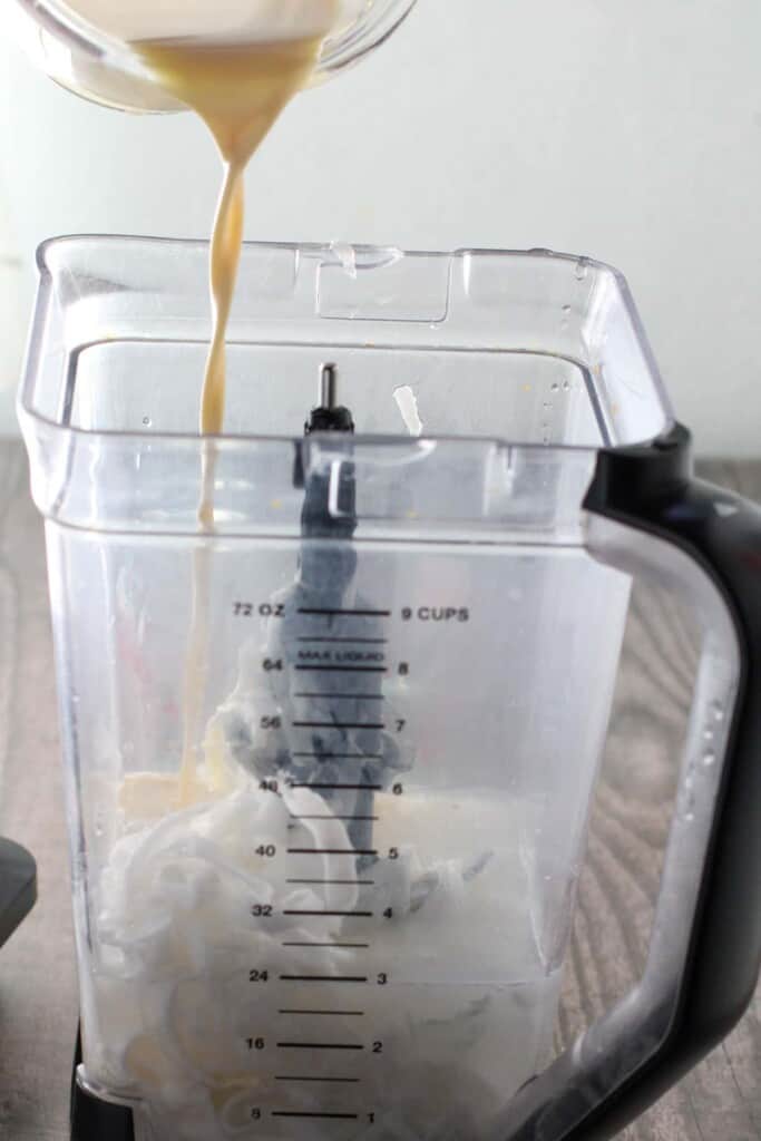 pouring evaporated milk in a blender with young coconut