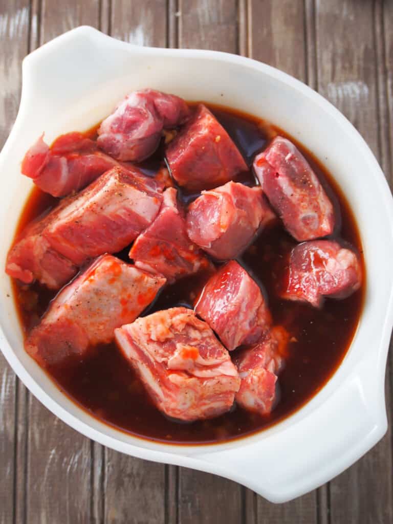 spare ribs marinating in ketchup, pineapple juice, and soy sauce in a bowl