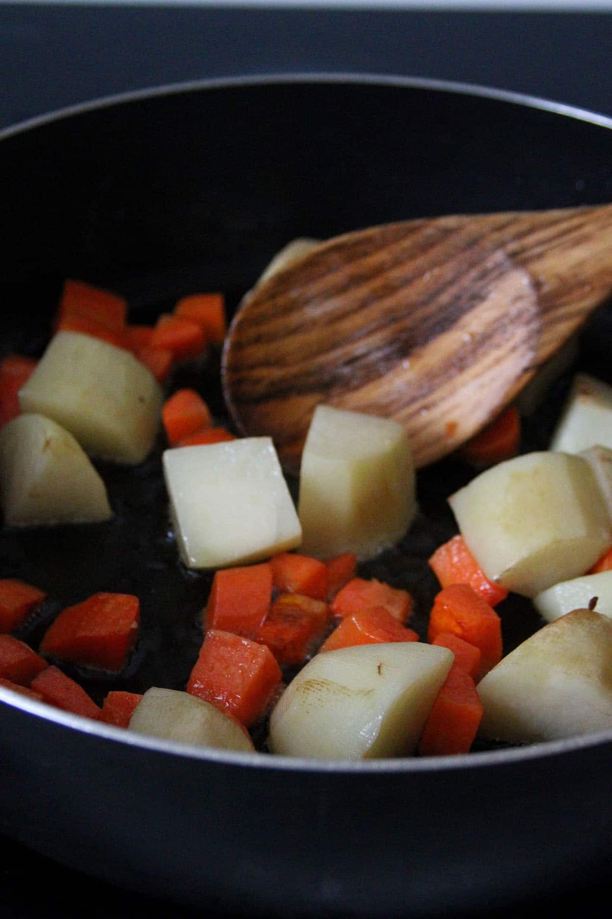 frying potatoes and carrots in a pan