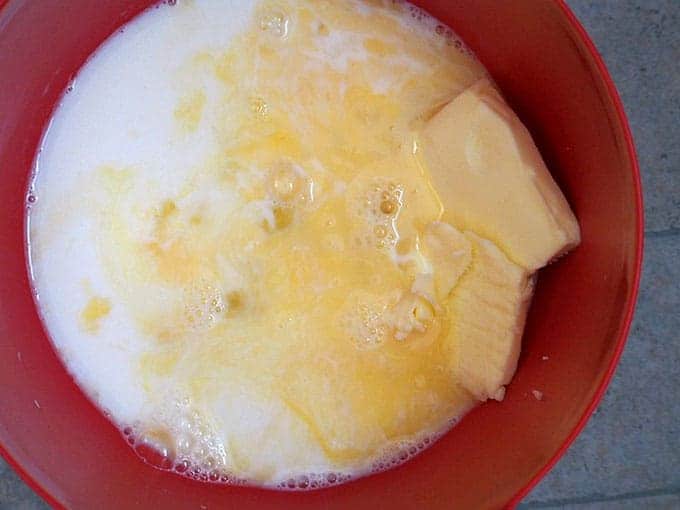 milk, butter , eggs, sugar, and salt in a red bowl to make pandesal