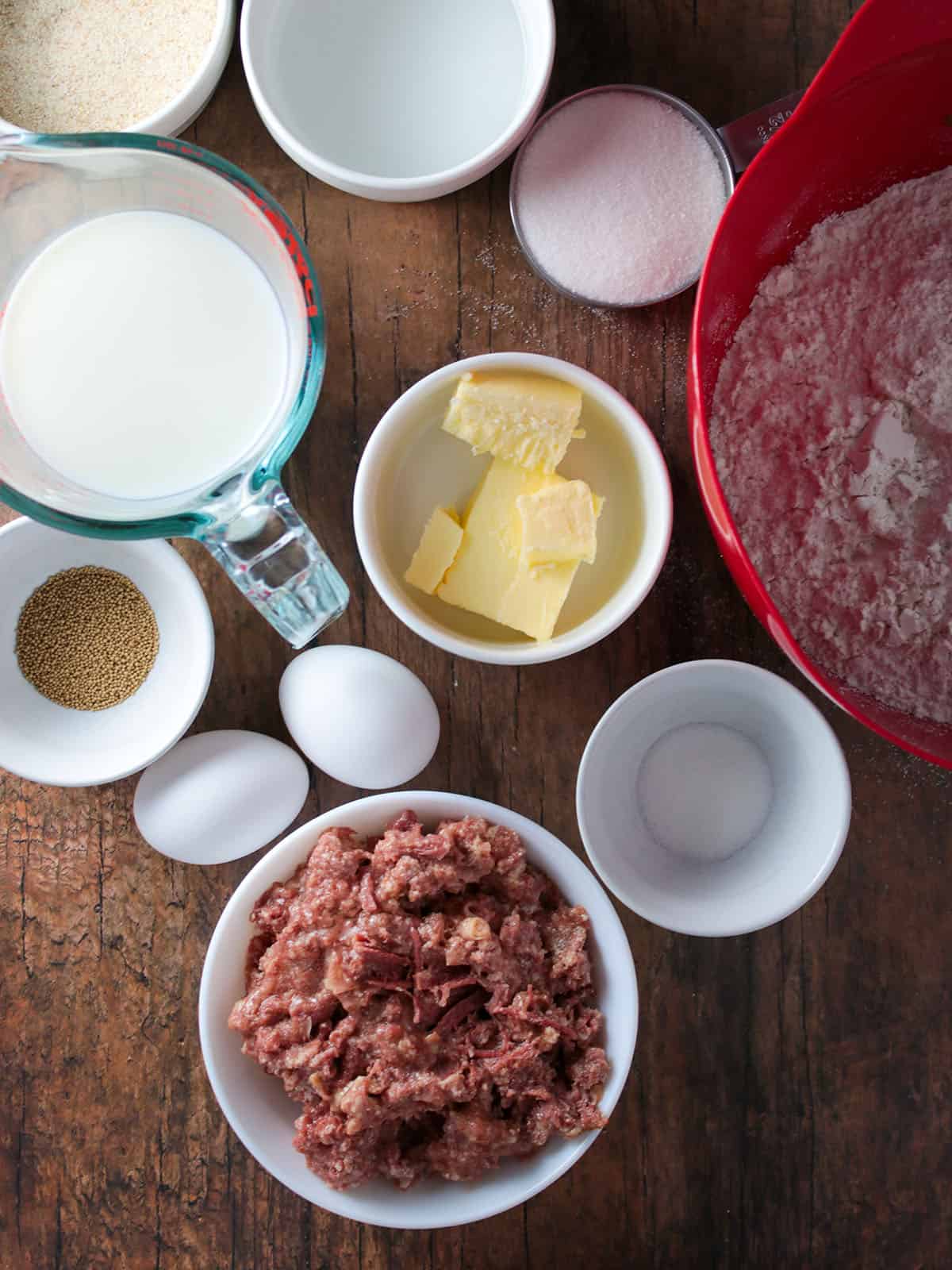 flour, corned beef, butter, eggs, yeast, milk, water, bread crumbs, sugar, salt in bowls