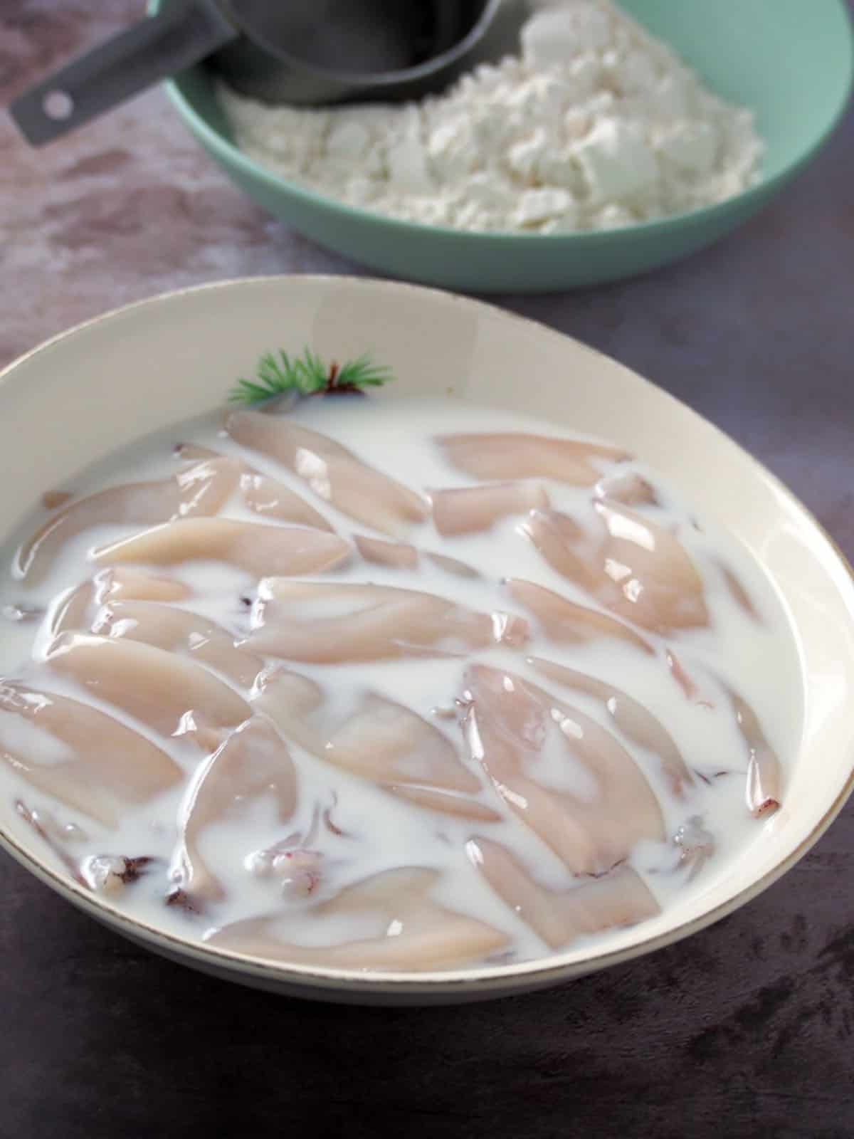 cleaned squid soaking in milk in a bowl