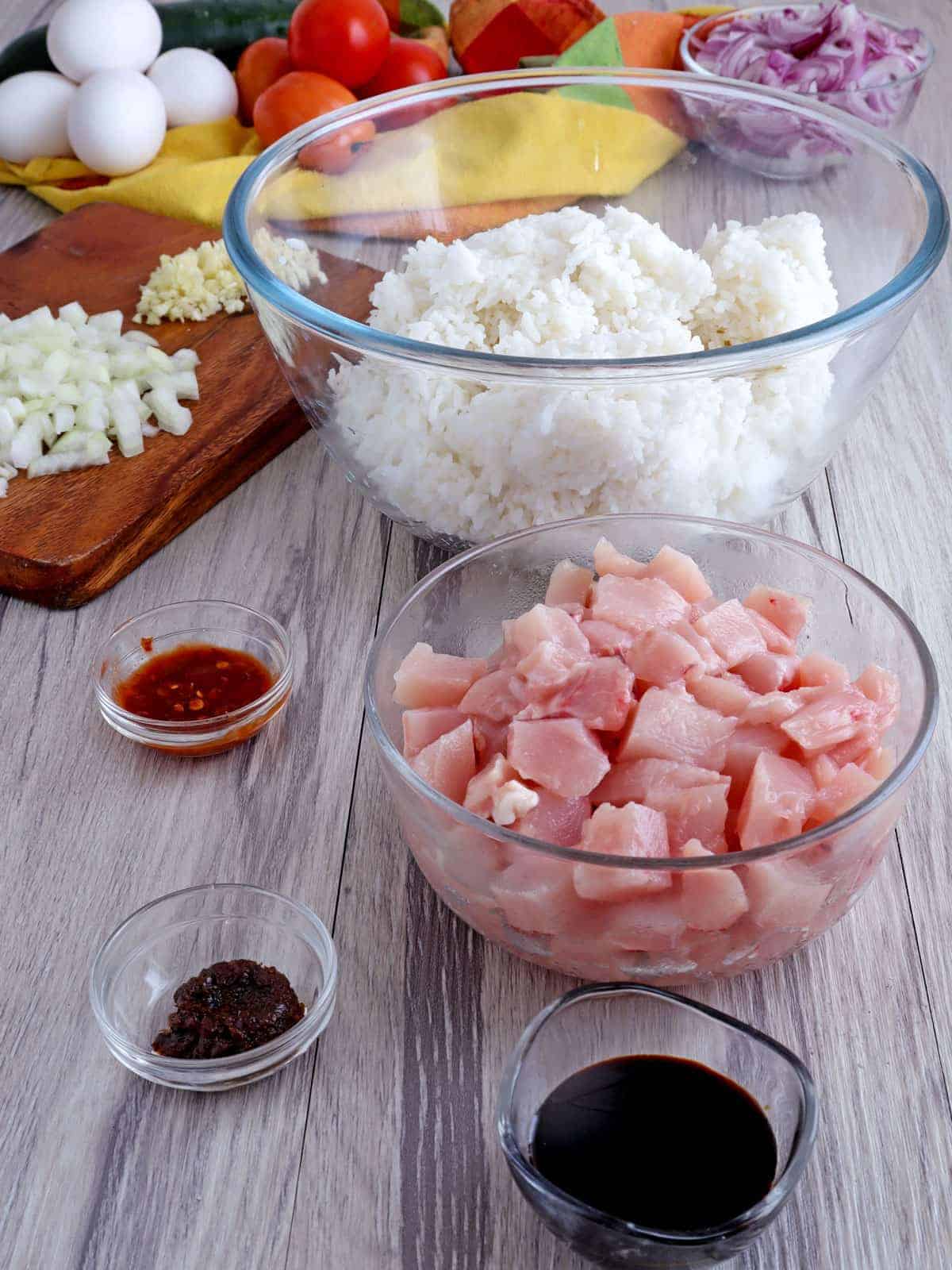 cut-up chicken breast, steamed rice, kecap manis, shrimp paste in bowls