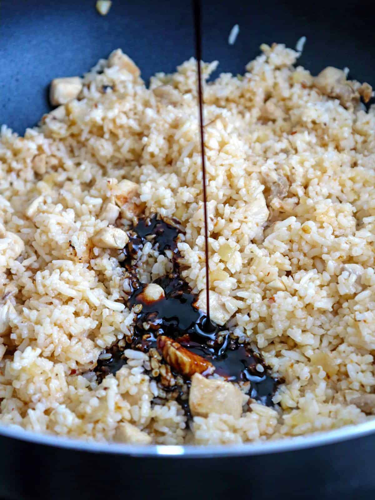 adding kecap manis to fried rice in a pan