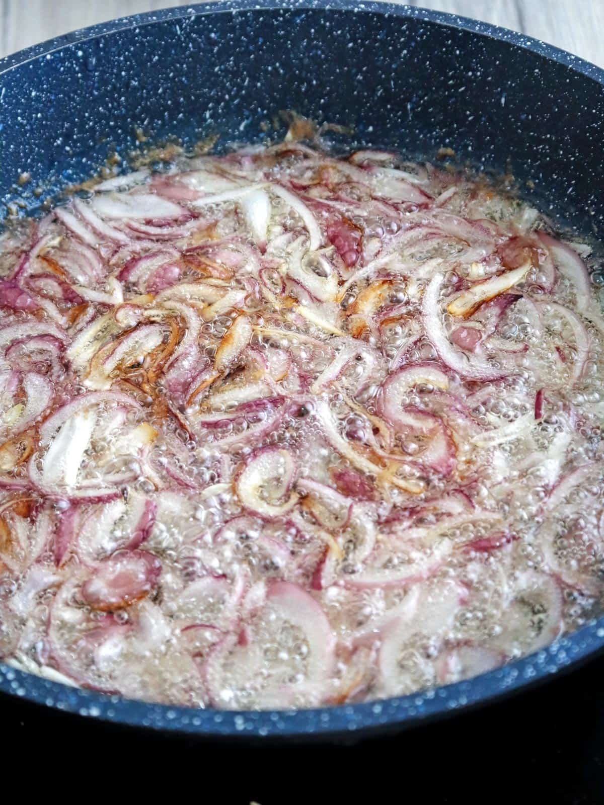 deep-frying sliced shallots in hot oil in a pan