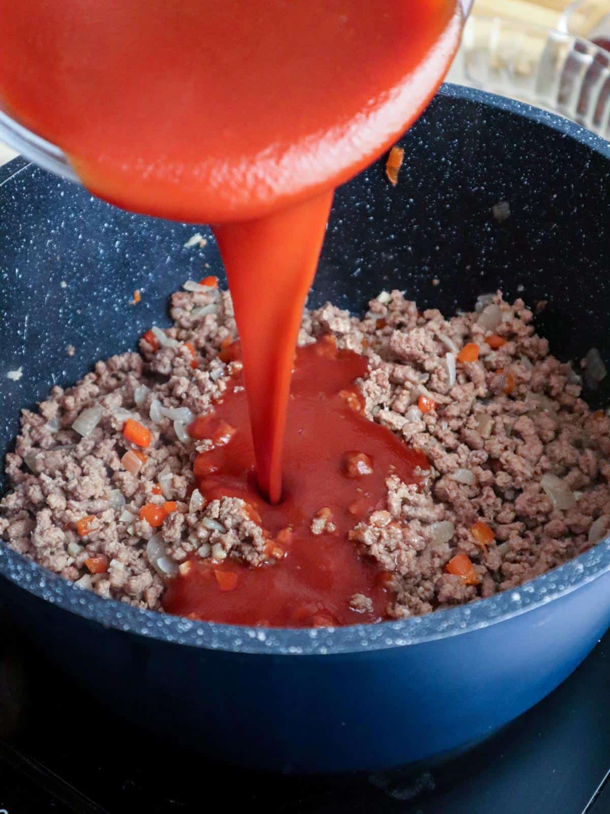 making meat sauce with tomato sauce in a pot