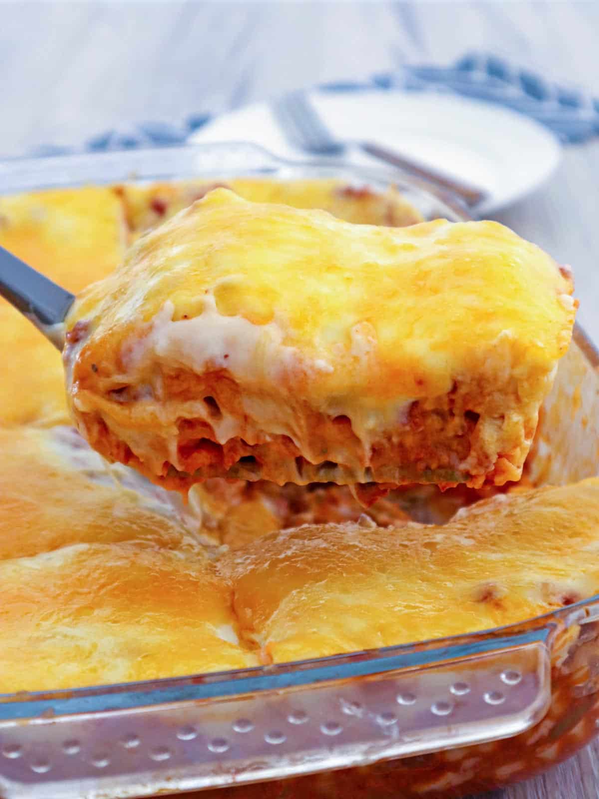 serving Cheesy lasagna with bechamel sauce layers from a baking dish with a spatula