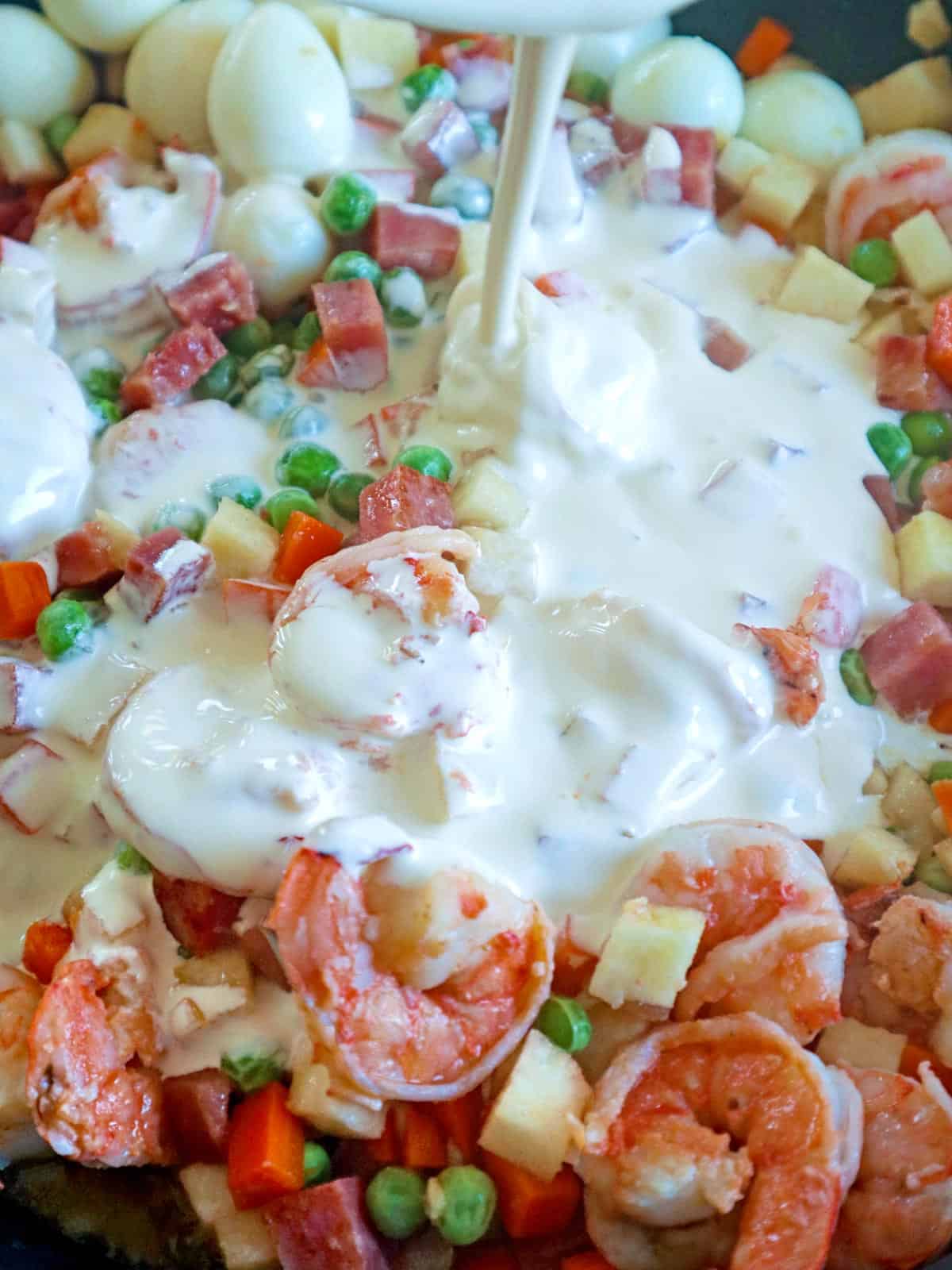pouring cream on sauteed shrimp and mixed veggies