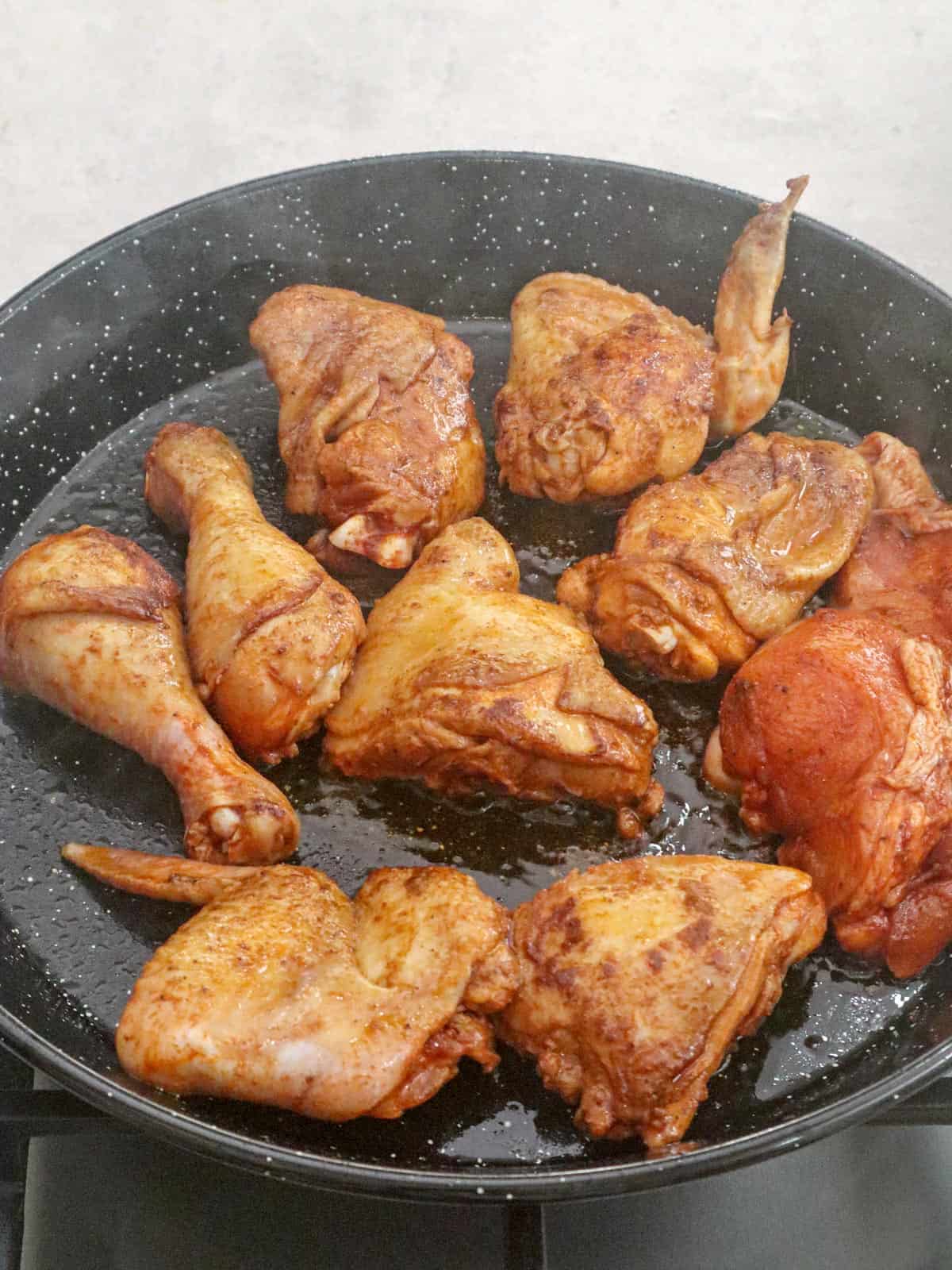 browning seasoned chicken in a paellera
