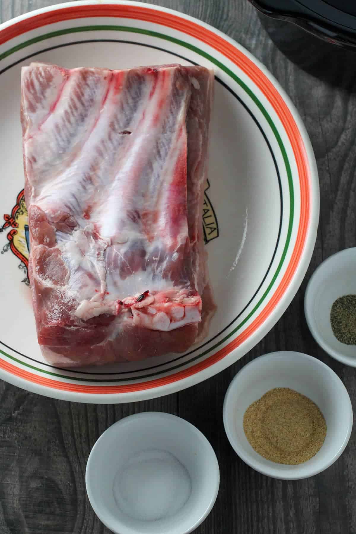 pork belly with ribs and seasonings in individual bowls