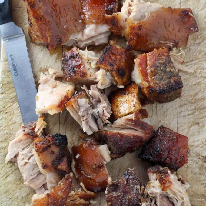 chopped slow cooker crispy pork belly on a wooden cutting board
