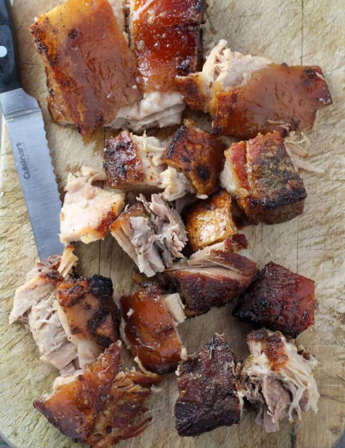 chopped slow cooker crispy pork belly on a wooden cutting board