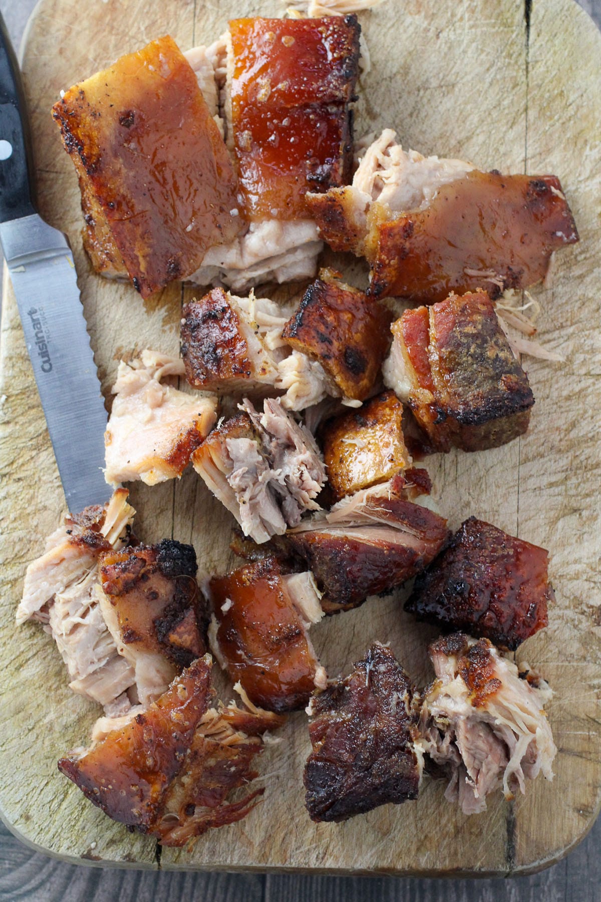 chopped slow cooker crispy pork belly on a wooden cutting board