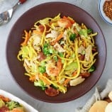 Pancit Lomi Guisado on a serving plate with pandesal on the side