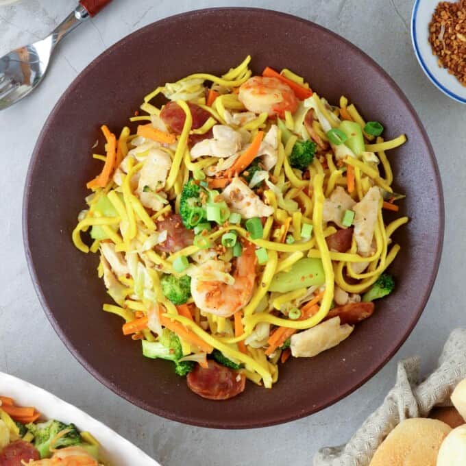 Pancit Lomi Guisado on a serving plate with pandesal on the side