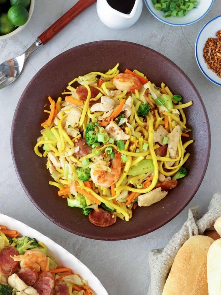 Pancit Lomi Guisado on a serving plate with pandesal on the side