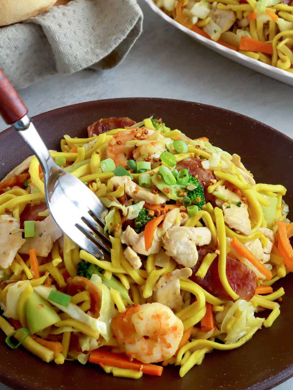 serving pancit lomi guisado with a fork from a plate