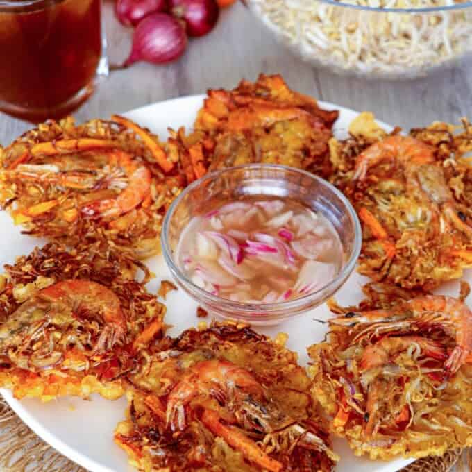 Shrimp and Vegetable fritters on a white plate with a bowl of spicy vinegar