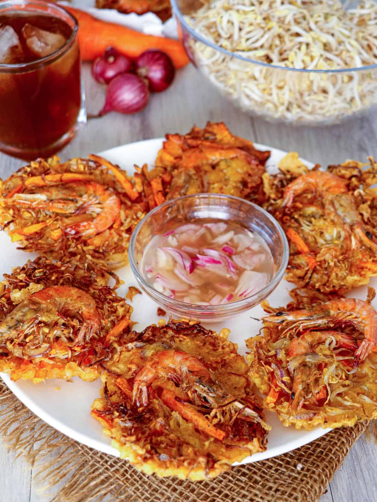 Shrimp and Vegetable fritters on a white plate with a bowl of spicy vinegar