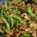 chicken stir fry with cashew and snow peas in a pan