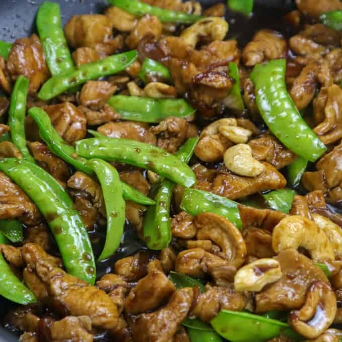chicken stir fry with cashew and snow peas in a pan