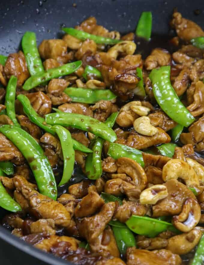 chicken stir fry with cashew and snow peas in a pan
