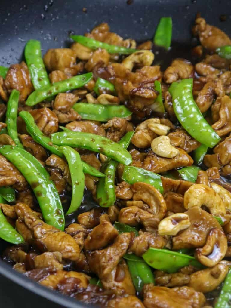 chicken stir fry with cashew and snow peas in a pan