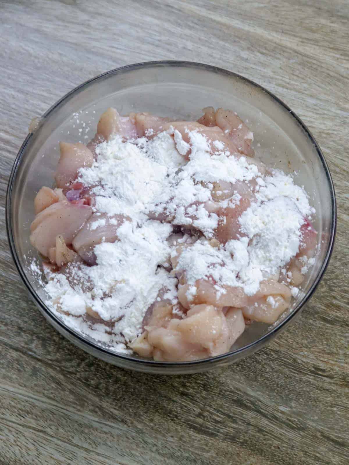 marinating chicken in cornstarch in a bowl