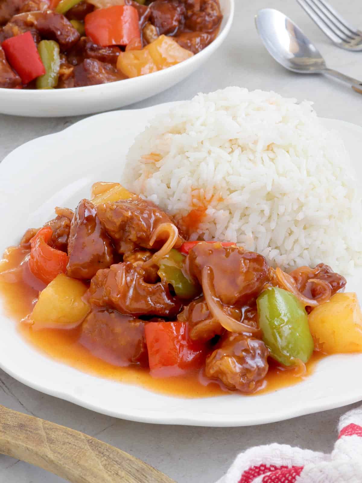 crispy pork with pineapple glaze on a white plate with steamed rice